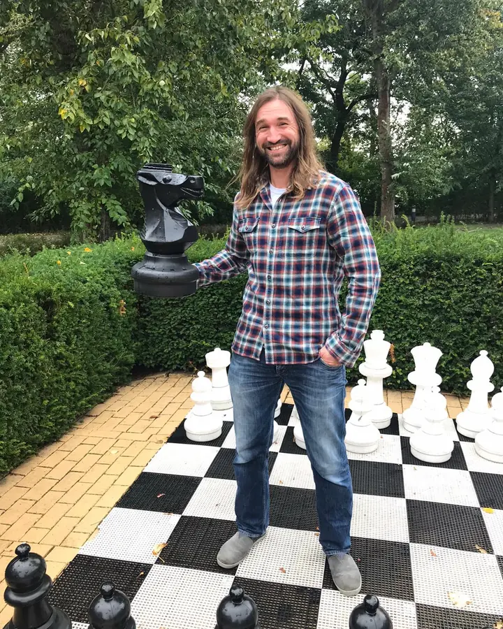 Toni Hoffmann aus Lutherstadt Eisleben auf einem großen Schachbrett im Freien, mit einer schwarzen Springerfigur in der Hand